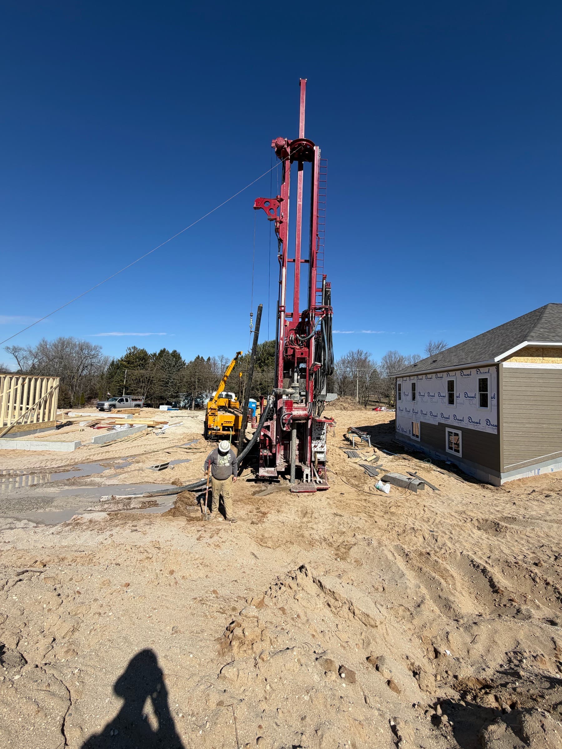 Sam's Well Drilling rig on a muddy residential job site — the company DrillerDB was built inside